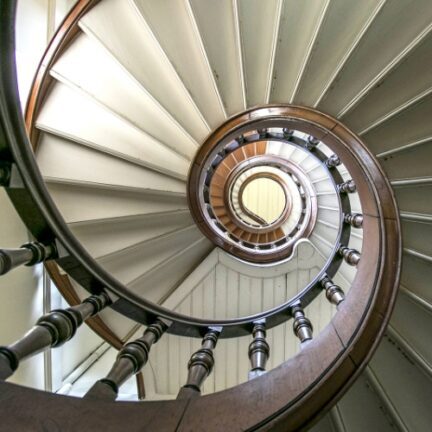 Spiral staircase. The staircase has dark wood handrails. The steps are in light wood.