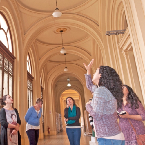 Pessoas em um dos corredores do Edifício-Monumento. Uma mulher tem um braço erguido com a mão aberta apontando para o teto.