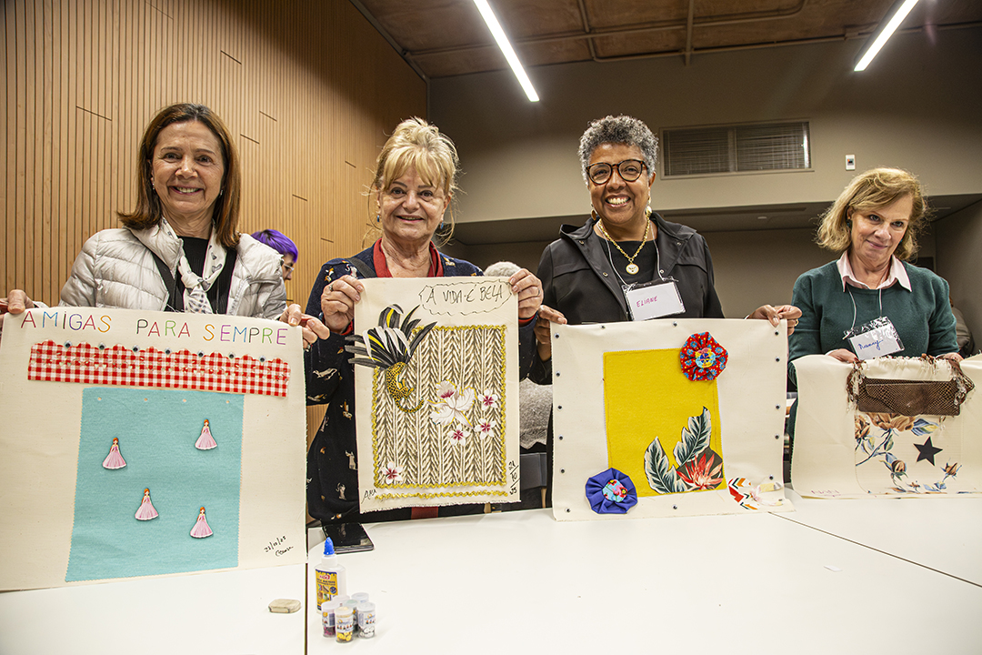 Quatro mulheres idosas seguram trabalhos artísticos produzidos em oficina durante uma edição anterior do curso “Construindo memória em um museu de história”, no Museu do Ipiranga