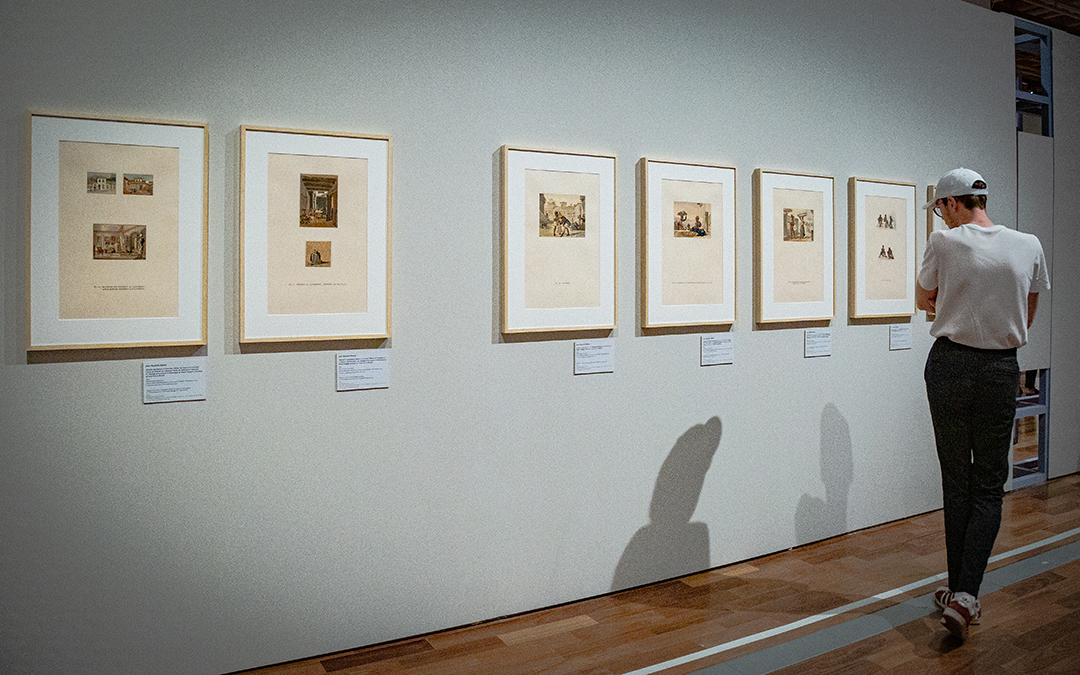 Pessoa observa gravuras de Debret alinhadas na parede da exposição “Debret em questão: olhares contemporâneos” do Museu do Ipiranga.